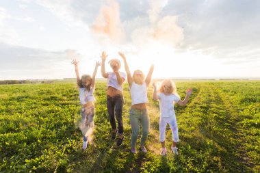 Hint bayram, eğlenceli ve Holi festival kavramı - mutlu kadın ve kız çocuklarının atlama boya atmak kadar renkli toz kaplı