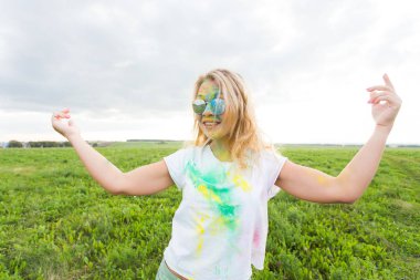 Eğlenceli, holi Festivali ve tatil kavramı - komik kadın doğa arka plan üzerinde gülümseyen renk toz kaplı