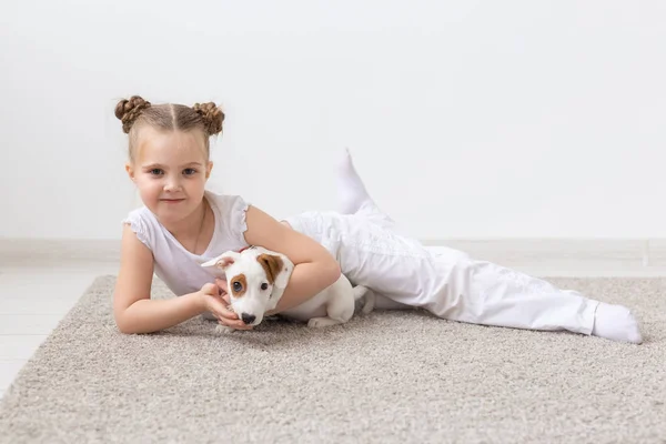 Concepto de la infancia, mascotas y perros - Niña posando en el suelo con el cachorro — Foto de Stock