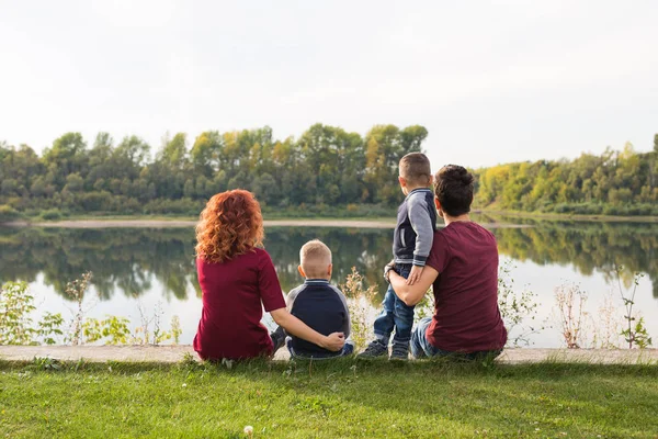 Barndom och natur koncept - familj med lite söner sitter på det gröna gräset — Stockfoto