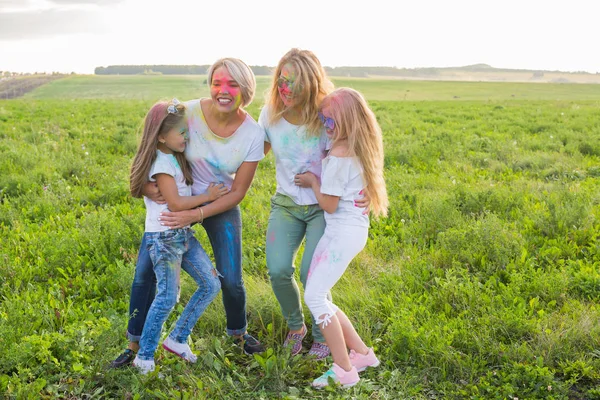 La amistad, las fiestas indias y el concepto de la gente - las mujeres jóvenes y los niños se divierten en el campo de verano en el festival de holi —  Fotos de Stock