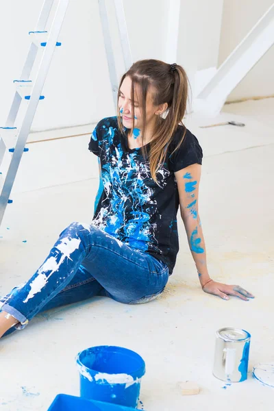 La gente, la renovación y el concepto de interiores - Mujer joven sentada en el suelo blanco y divertirse en el descanso — Foto de Stock