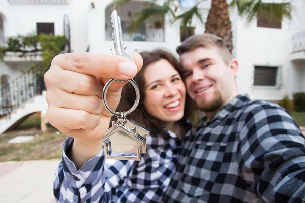 New Home, real estate and moving concept - Funny young couple showings keys from new house. — Stock Photo, Image