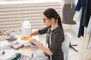 İnsanlar, terzi ve moda kavramı - yan görünüm portre moda tasarımcısı bardaklarda atölyede dikiş makinesi kullanma