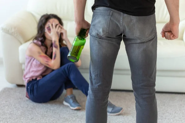 Slachtoffer, huiselijk geweld, misbruik en alcoholische concept-dronken man met fles in de buurt van zijn vrouw zittend op de vloer — Stockfoto