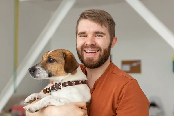 Animal, mascota y gente concepto - Hombre guapo y gato doméstico russell terrier perro posan juntos en el interior — Foto de Stock