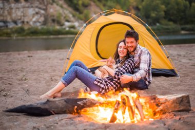 Kişi, turizm ve doğa kavram - bir ateşin yanında oturan adam embrace kadın