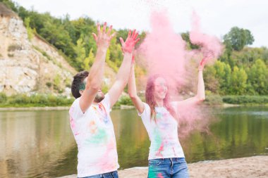 Festival holi, tatil, turizm ve doğa kavramı - çift renkli toz ile oynayan beyaz gömlek giymiş