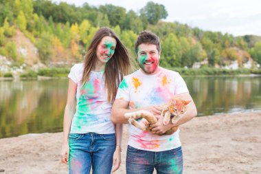Festival holi, turizm ve doğa kavramı - kadın ve erkek kedi ile portre çok renkli toz kaplı.