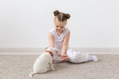 Çocuk ve hayvan kavramı - kız çocuk ve köpek yavrusu katta oturan pijama giymiş