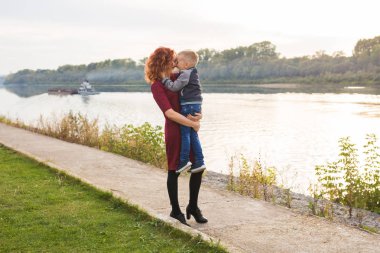 Annelik ve çocuk kavramı - genç anne ile oğlu Nehri yakınında kollarında