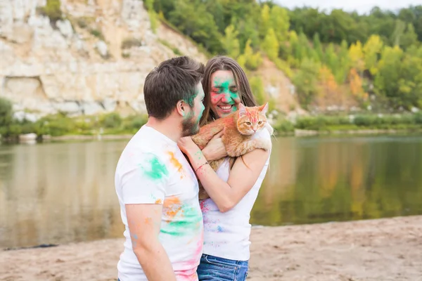 축제 holi, 관광 및 자연 개념-여자와 고양이 함께 남자의 초상화 덮여 멀티 컬러 먼지 — 스톡 사진