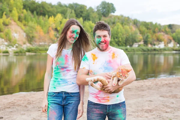 Festival holi, Tourismus und Naturkonzept - Portrait von Frau und Mann mit Katze bedeckt mehrfarbigem Staub — Stockfoto