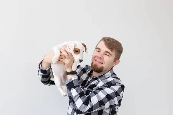 Concepto de personas, mascotas y animales - primer plano de hombre joven sosteniendo gato russell terrier cachorro sobre fondo blanco — Foto de Stock