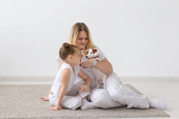 Concepto de personas, familia y mascotas madre e hija sentadas en el suelo con el cachorro Jack Russell Terrier —  Fotos de Stock