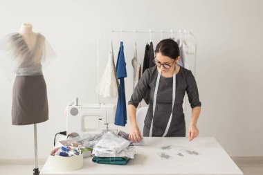Terzi, moda tasarımcısı ve terzi kavramı - genç kadın moda tasarımcısı onu galeride çalışıyor