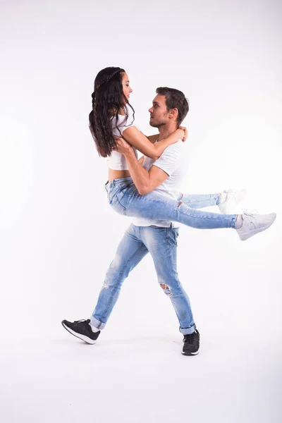 Pareja joven bailando baile social latino bachata, merengue, salsa. Dos poses de elegancia sobre fondo blanco — Foto de Stock