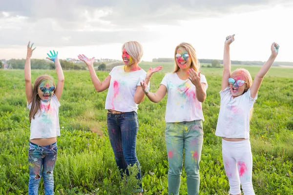 Festival de Holi, la amistad, las vacaciones y el concepto de la gente - Saltar mujeres y niñas felices cubiertos de pintura —  Fotos de Stock