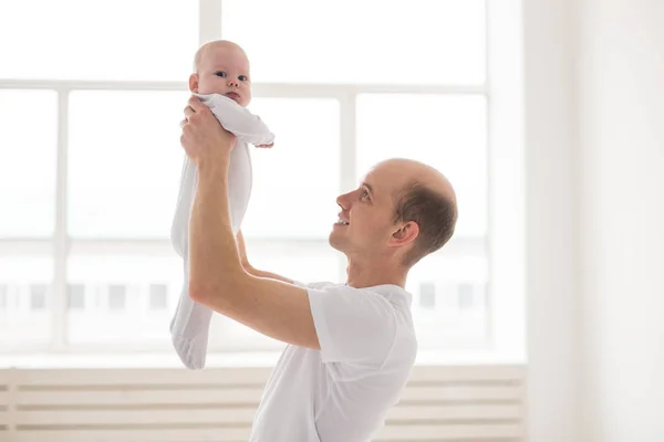 Concepto de familia, paternidad e hijos - padre calvo sosteniendo lindo recién nacido en casa — Foto de Stock