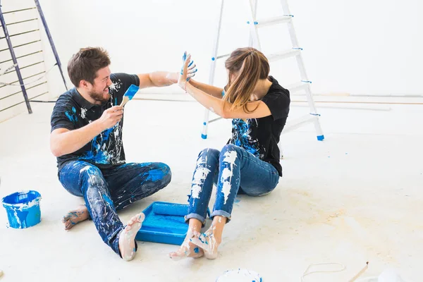 Renovasyon, yeniden dekorasyon ve iç konsept-beyaz katta oturan genç çift ve boya dökmek ve eğlenmek — Stok fotoğraf
