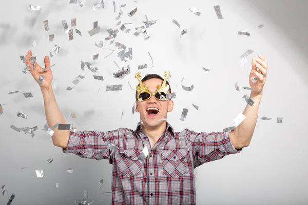 Menschen, Urlaub und Party-Konzept - lustiger Typ in Gläsern, der in Konfetti auf weißem Hintergrund tanzt — Stockfoto