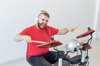 İnsanlar, müzik ve hobi konsepti - Beyaz kulaklıklı adam, hafif arka plan üzerinde geçen davulları çalıyor