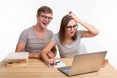 İnsanlar ve eğitim kavramı - laptop ve Kitaplar ile tahta masada oturan iki mutlu komik öğrenci