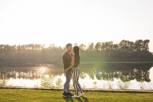 Понятие природы и людей - молодая пара целуется на пляже озера и обнимается — стоковое фото