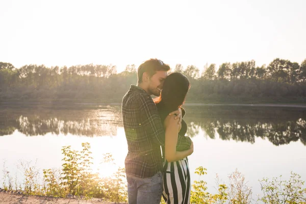 Ρομαντικό, αγάπη, άνθρωποι έννοια - ζευγάρι αγκαλιάζει κοντά στην λίμνη στο ηλιοβασίλεμα — Φωτογραφία Αρχείου