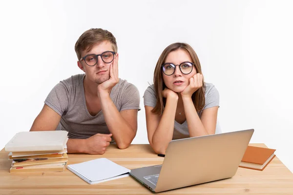 Istruzione e concetto di persone - coppia di giovani con gli occhiali sembrano stufi di imparare a fare i compiti — Foto Stock