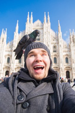 Kış seyahat, tatil ve kuşlar kavramı - yakışıklı erkek turist Milano'da ünlü Duomo Katedrali önünde selfie fotoğraf yapma komik güvercinler ile.