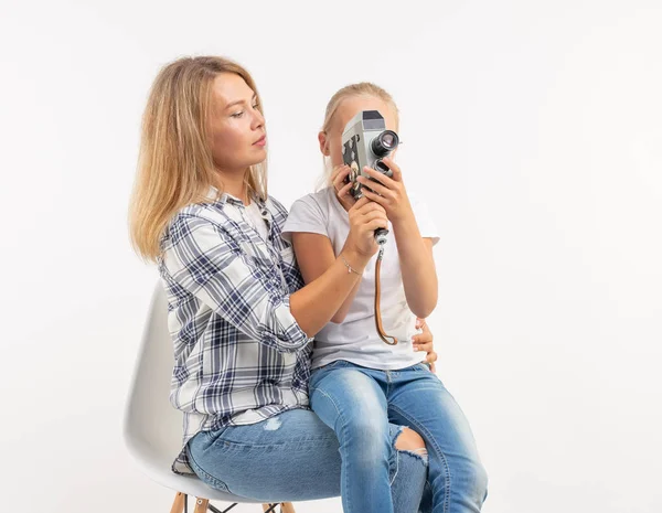 Foto's, fotograaf en retro camera concept - jonge vrouw en haar tiener dochter met behulp van vintage camera op witte achtergrond — Stockfoto