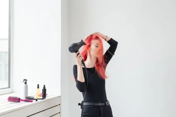 Стилист, мода, парикмахер, люди концепции - женщина сушит свои цветные волосы у окна — стоковое фото