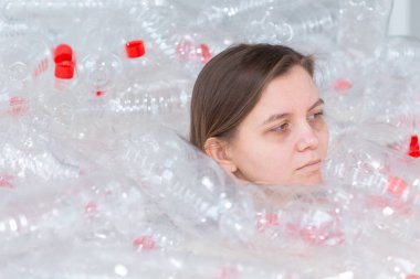 Susuz kalmış hasta kadın plastik şişeyığının içinde yatıyor. Çevre kirliliği sorunu. Doğaçöp çevre koruma konsepti durdurun