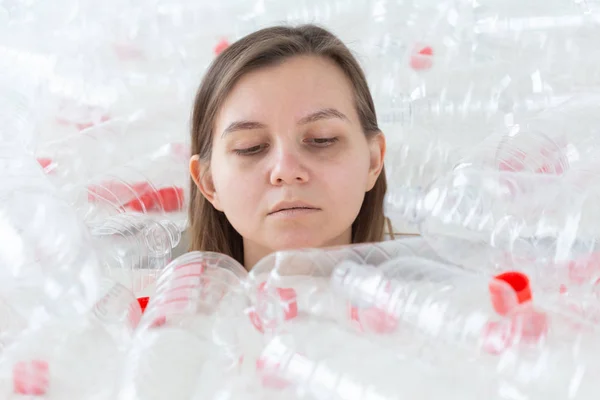 Plastic pollution problem and environment protection. Weak tired woman in a pile of plastic bottles. Save Earth concept. Clean our nature.