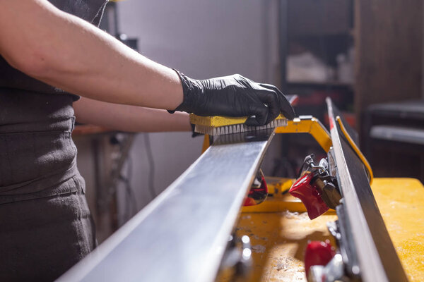Work and repair concept - a mans hands repairing the ski by rubbing a paraffin