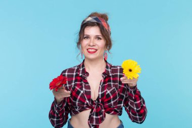 Gerberas, pin-up ve eğlenceli konsept - mavi arka plan üzerinde retro tarzı çiçekler ile neşeli genç kadın