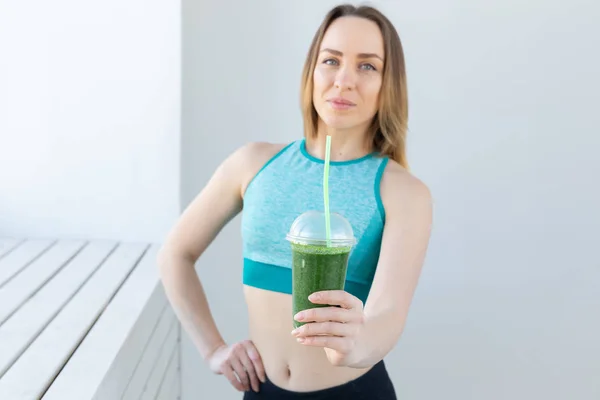 Healthy, sport, diet and people concept - Successful fitness urban woman recommending detox smoothie