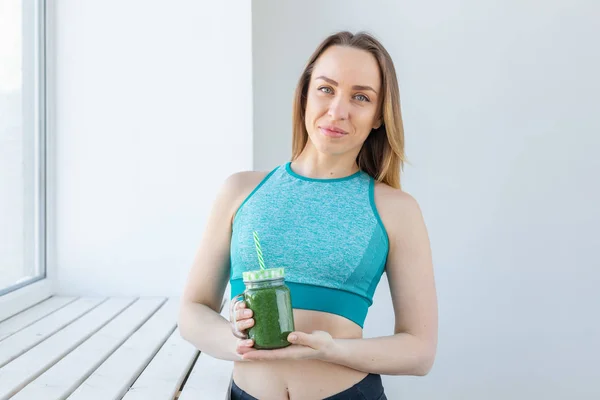 Sano, dieta, disintossicazione e perdita di peso concetto - giovane donna in abbigliamento sportivo con frullato verde — Foto Stock