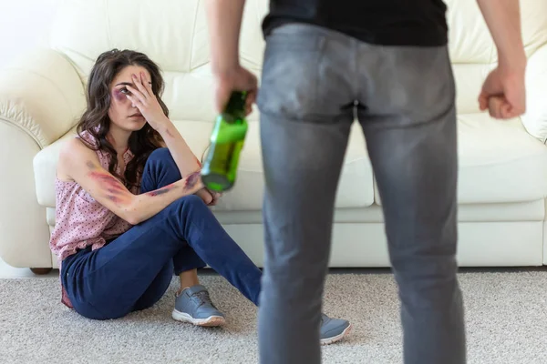 Przemocy domowej, alkoholu i nadużyć koncepcja-pijany człowiek z butelką nadużywanie jego żona siedzi na podłodze — Zdjęcie stockowe
