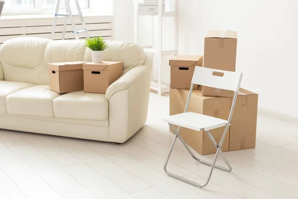 Sofá cadeira dobrável e caixas estão na nova sala de estar quando os moradores se mudam para um novo apartamento. O conceito de novos edifícios e habitação confortável para os jovens . — Fotografia de Stock