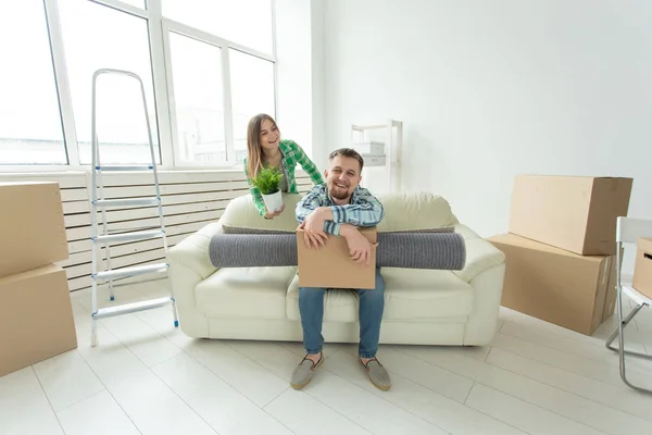 Веселая молодая пара радуется переезду в новый дом, раскладывая свои вещи в гостиной. Концепция новоселье . — стоковое фото