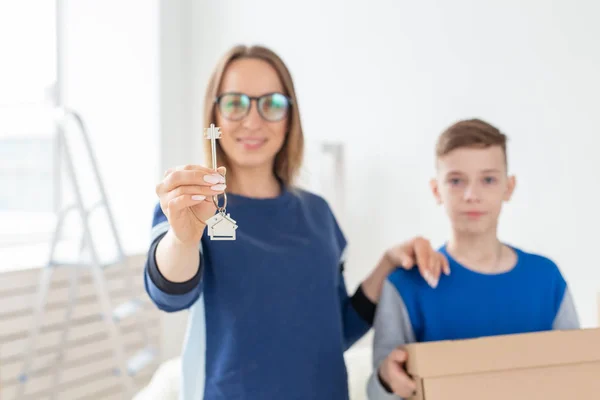После новоселья размытые, хорошо выглядящие мама и сын держат ключи от новой квартиры. Новая концепция и варианты ипотеки для молодой семьи . — стоковое фото
