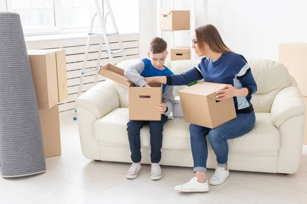 Die süße Mutter und der kleine Sohn sortieren nach dem Umzug Kisten mit Sachen. das Konzept der Eigenheimhypothek und die Freude am neuen Wohnraum. — Stockfoto