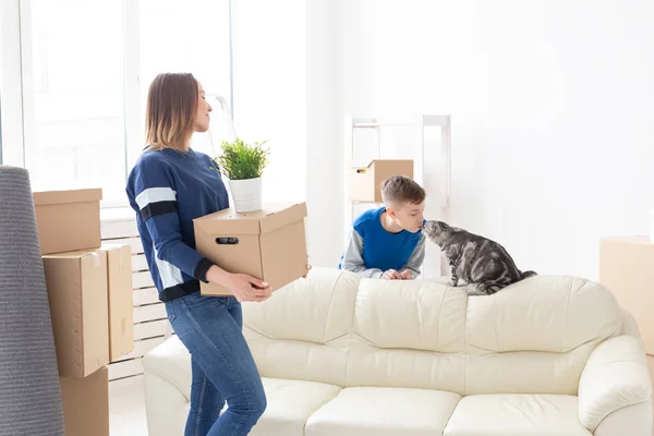 Schlanke positive junge Mutter und ein niedlicher Sohn arrangieren die Dinge und kommunizieren mit ihrer schottischen Faltenkatze. Erwärmung und Umsiedlungskonzept — Stockfoto