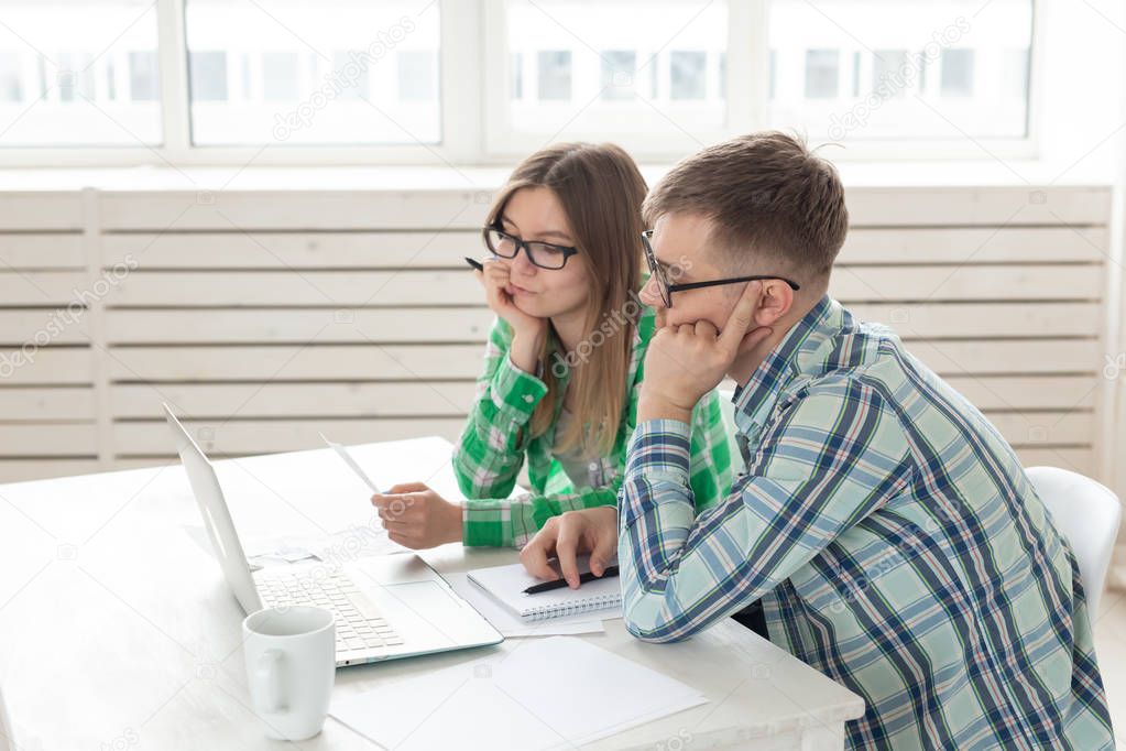 Dissatisfied young husband and wife recount utility bills for payment of an apartment and write the results in a notebook and laptop in their home accounting.