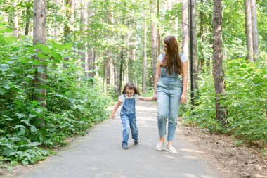 Aile, Doğa ve insan kavramı - anne ve kızı zaman harcamak birlikte yeşil parkta bir yürüyüş üzerinde
