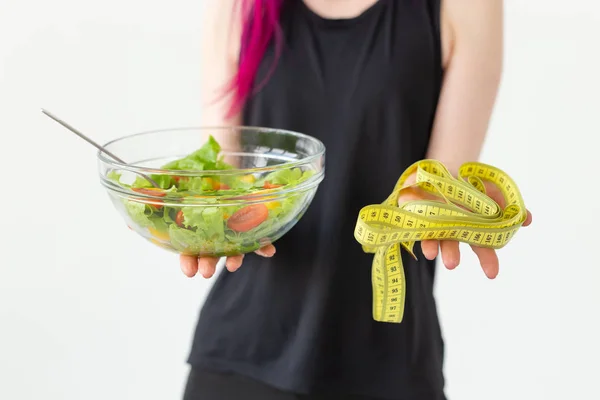 Jeune blogueuse de fitness non identifiée tenant une salade de légumes et un ruban à mesurer. Concept de style de vie sportif et bonne nutrition . — Photo