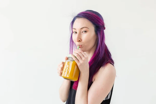 Menina bonito jovem hipster de raça mista com cabelos coloridos bebe smoothie fruta antes de iniciar uma aula de ioga em um fundo branco. Conceito de estilo de vida saudável. Copyspase . — Fotografia de Stock