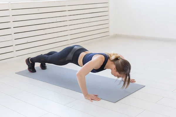 Gente, sano y deportivo concepto- Joven mujer atractiva deportiva haciendo flexiones — Foto de Stock